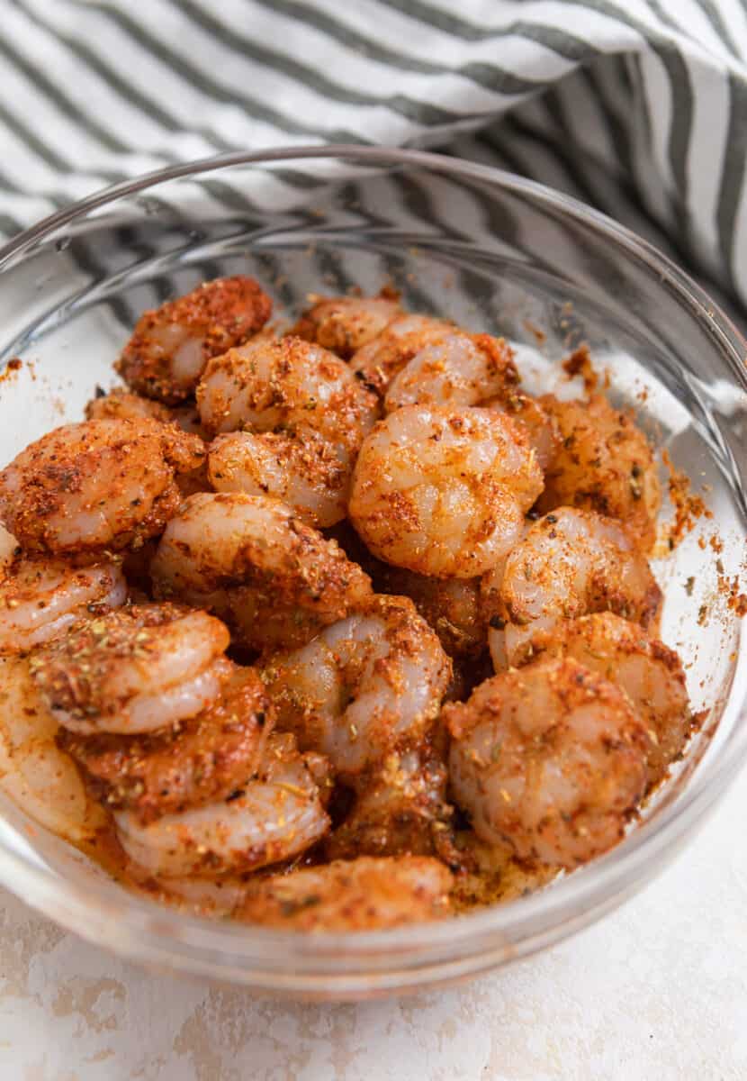 Raw shrimp in glass bowl with taco seasoning.