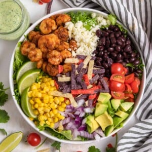 Shrimp taco salad with cheese, beans, avocado, corn, onion, and other ingredients.