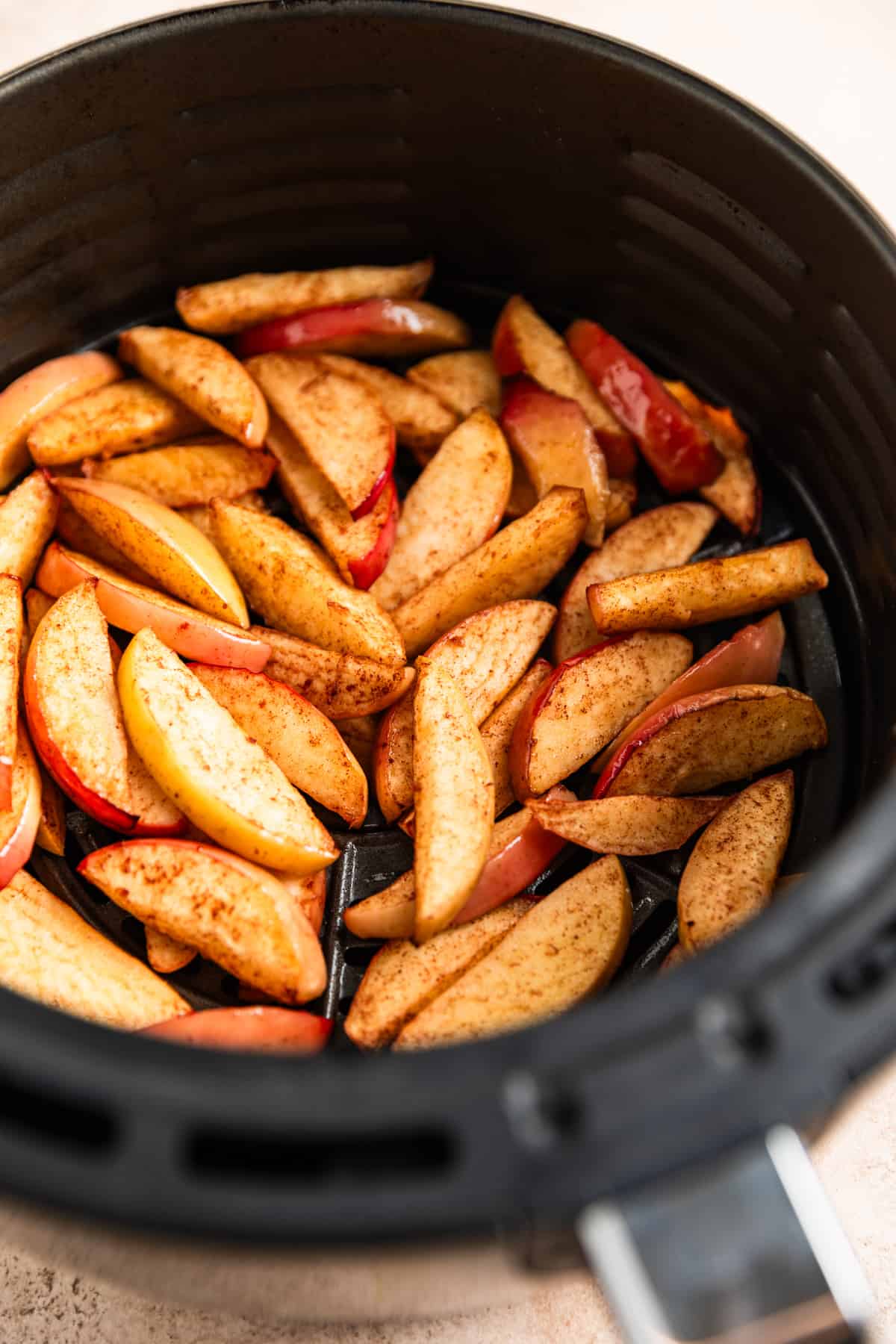 Cooked apple slices in air fryer basket.