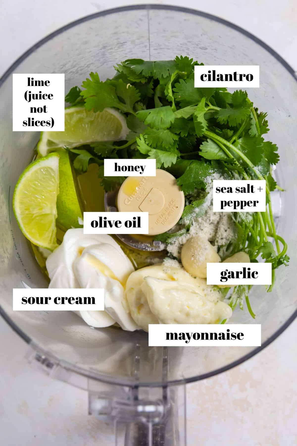 Food processor with cilantro, lime, mayo and other ingredients for dressing.