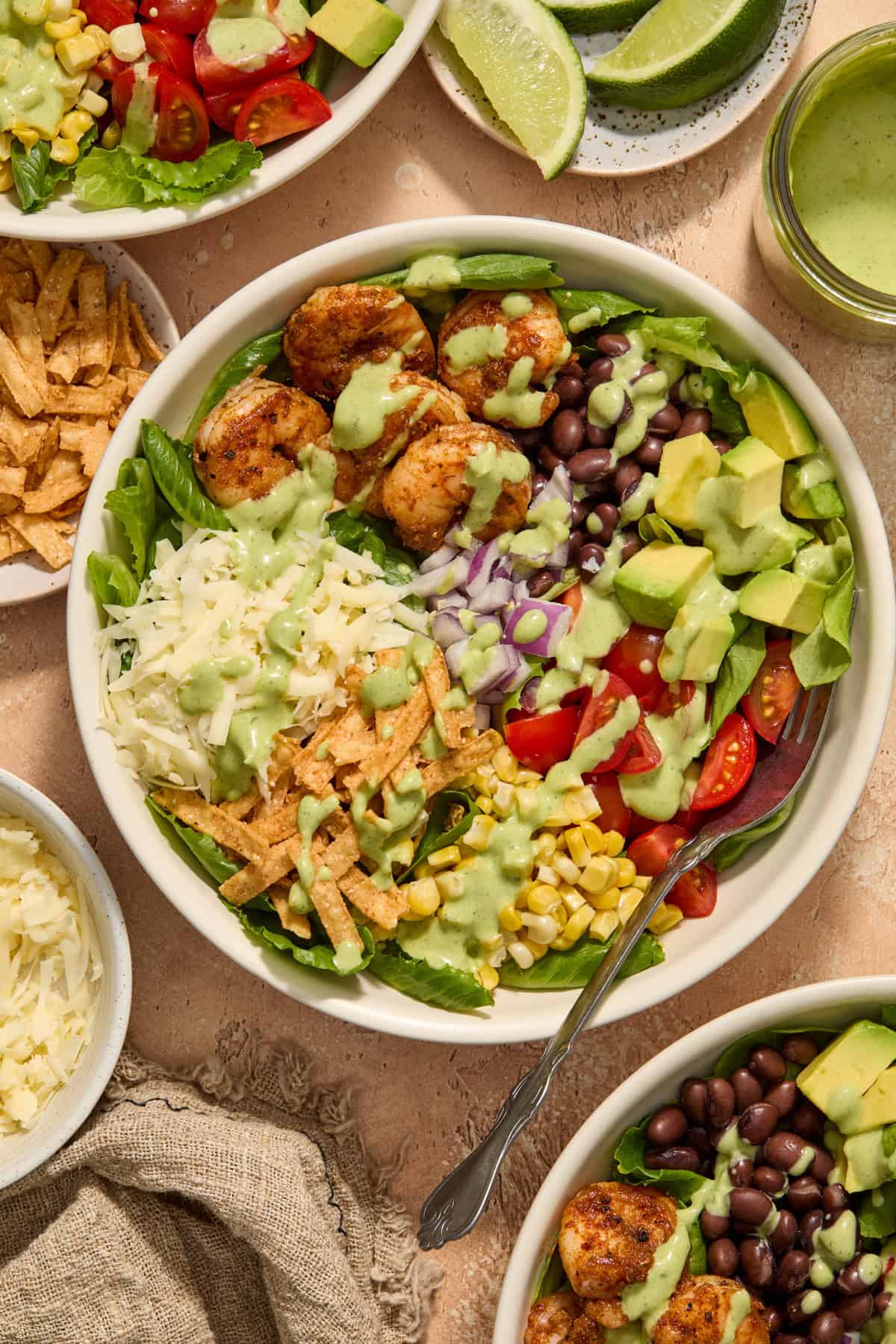 Overhead view of shrimp taco salad in bowl with seasoned shrimp, corn, avocado, cheese and more.