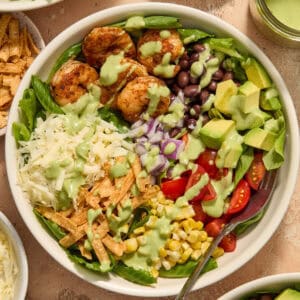 Taco salad in white bowl with sautéed shrimp, tomatoes, black beans, cheese and other ingredients.