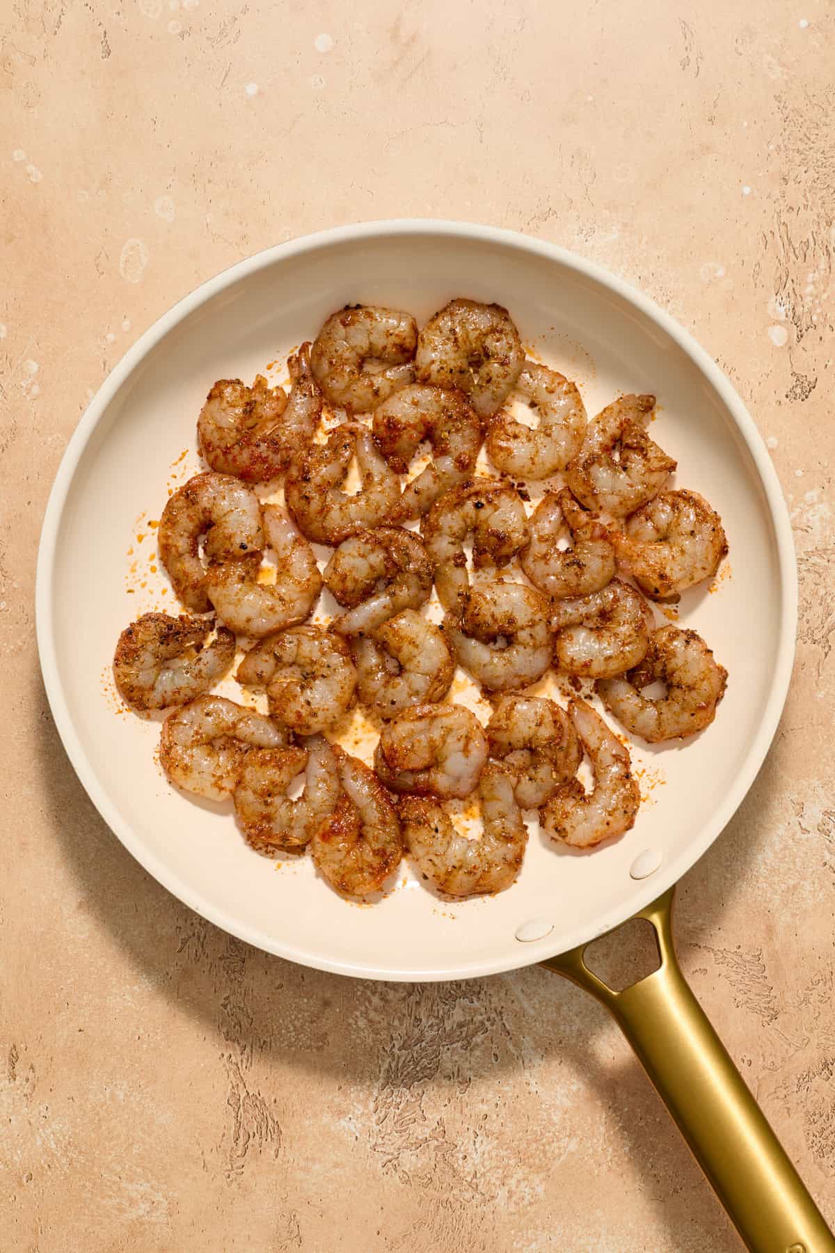 Marinated and seasoned shrimp in skillet.