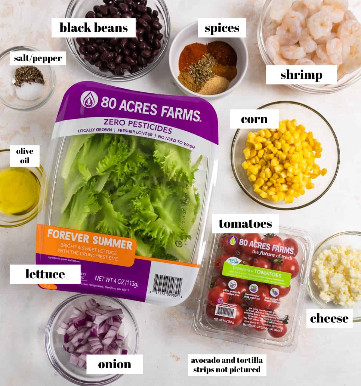 Lettuce, tomatoes, beans, shrimp, cheese and other ingredients for recipe labeled on counter.