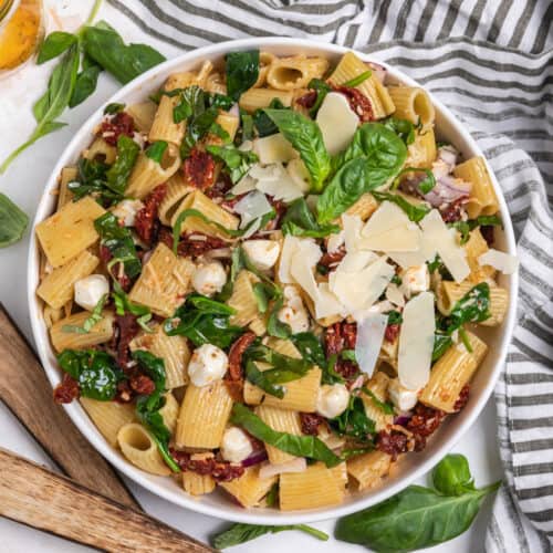 Overhead view of sun dried tomato pasta salad with mozzarella, basil, parmesan and spinach.