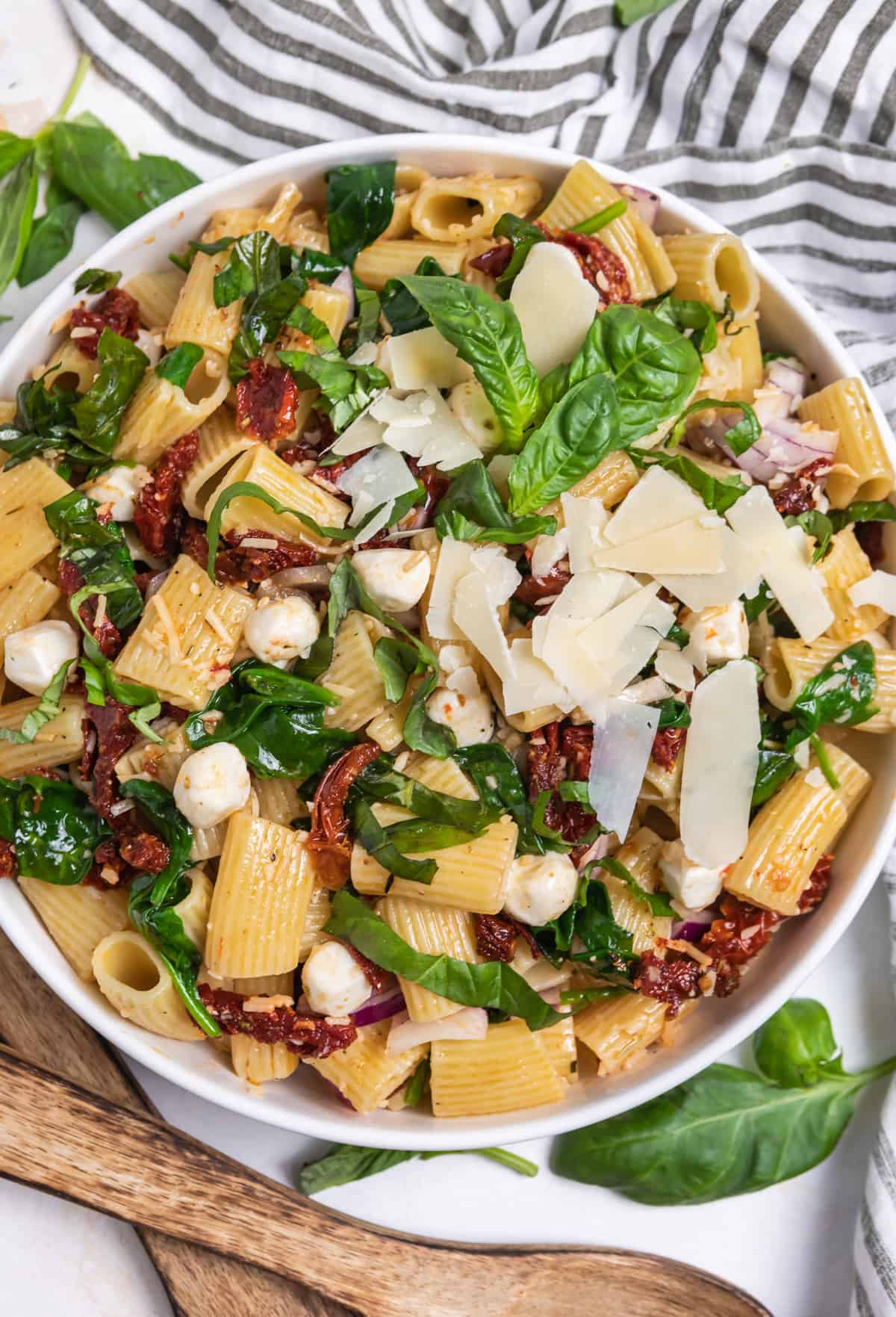Overhead view of sun dried tomato pasta salad with fresh basil, mozzarella and parmesan on top.