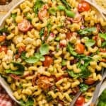 Salad bowl with sun dried tomato pasta salad with fork and soon scooping in.