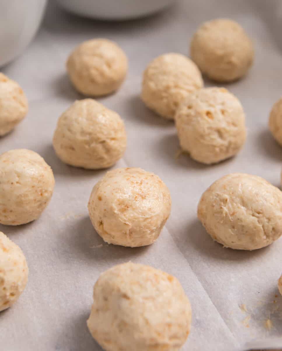 No bake cheesecake bites rolled into balls on parchment.