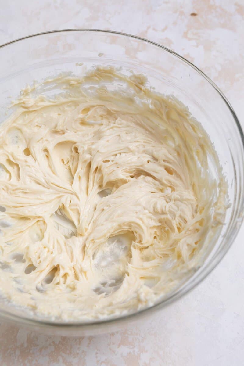 Cream cheese whipped with sugar and vanilla in glass mixing bowl.