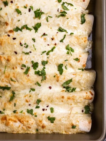 Pan of green chicken enchiladas with chopped cilantro on top.