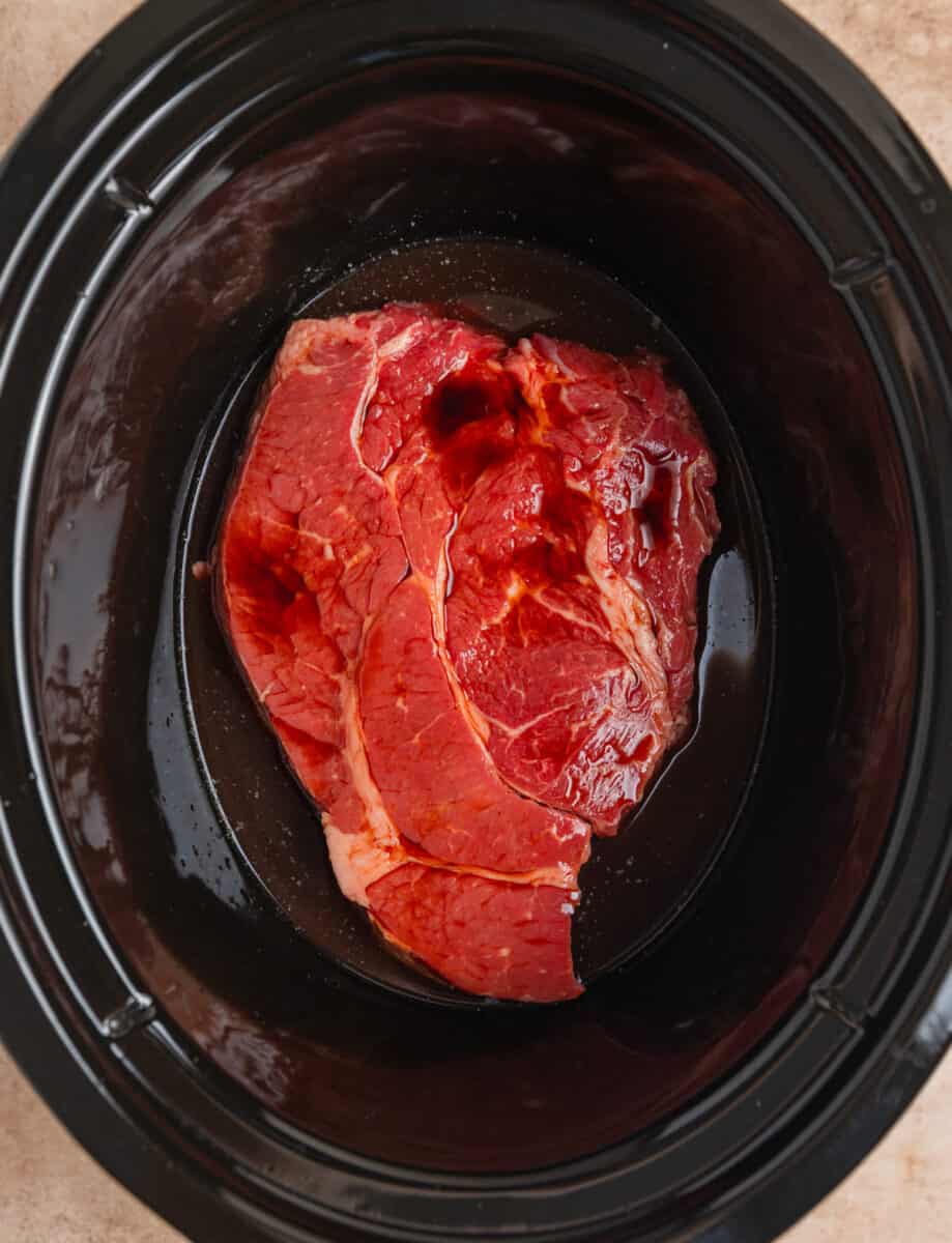 Soy sauce and other liquid poured over beef chuck roast in crock pot.