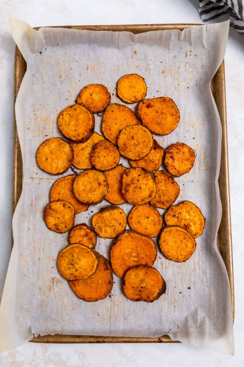 Roasted sweet potato rounds pulled together on parchment lined baking sheet.