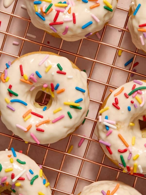 Vanilla donuts on cooling rack with vanilla glaze and sprinkles.