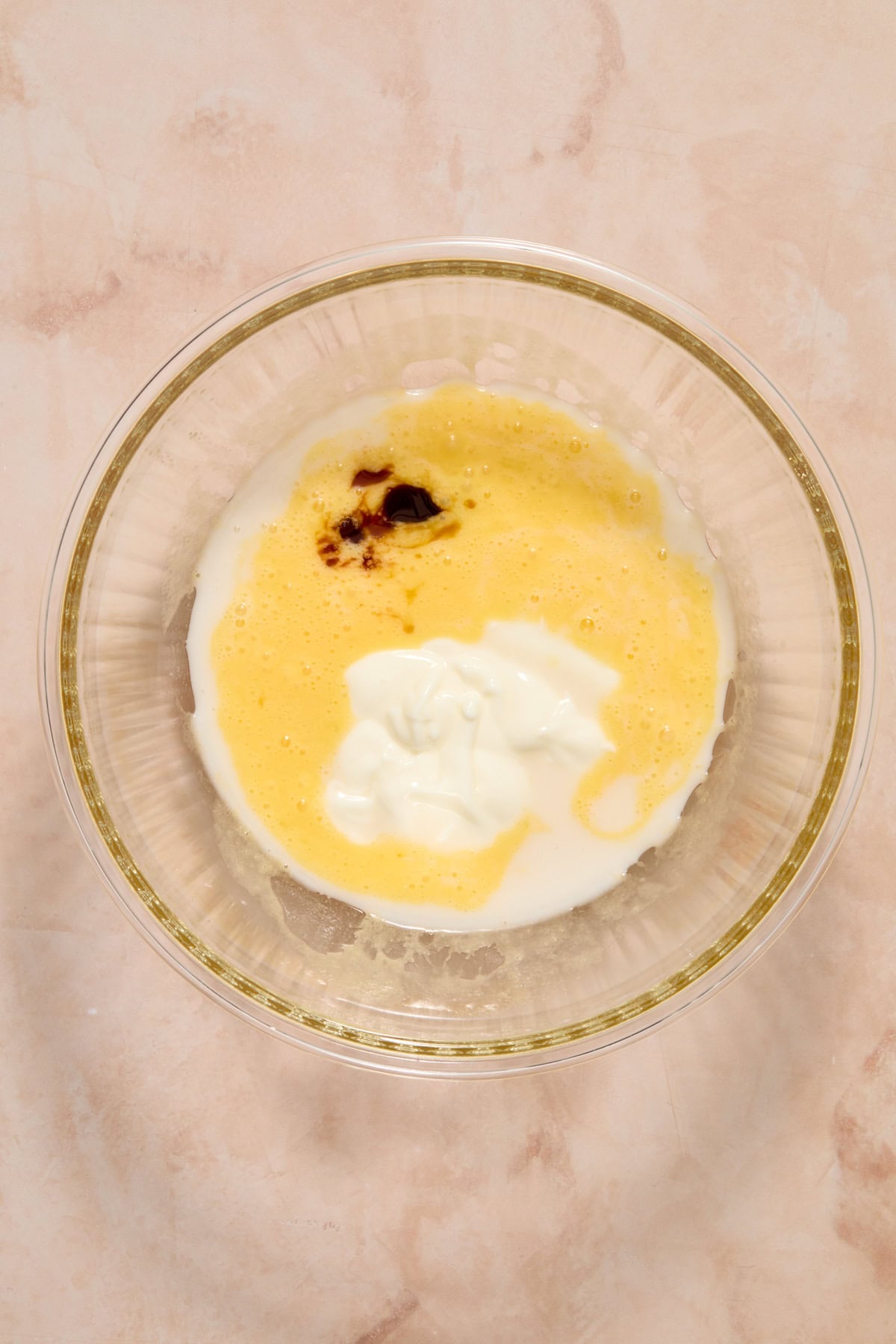 Vanilla yogurt and vanilla extract added to bowl with whisked sugar and butter.