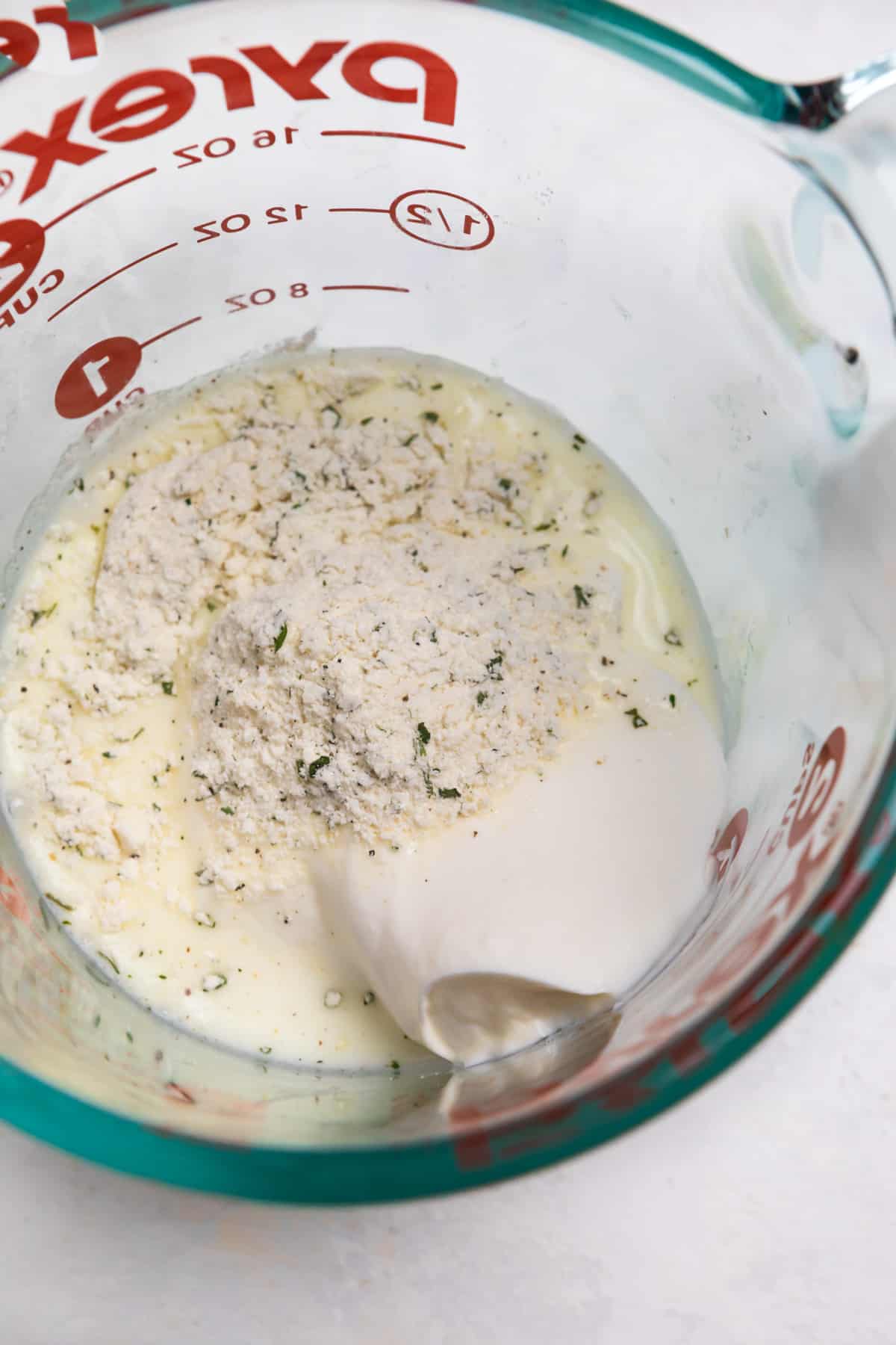 Pyrex measuring cup with ranch dressing ingredients.