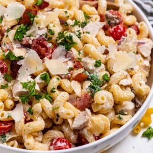 Bowl of pasta salad with chicken, bacon and ranch topped with parsley.