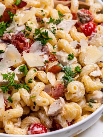 Bowl of pasta salad with chicken, bacon and ranch topped with parsley.
