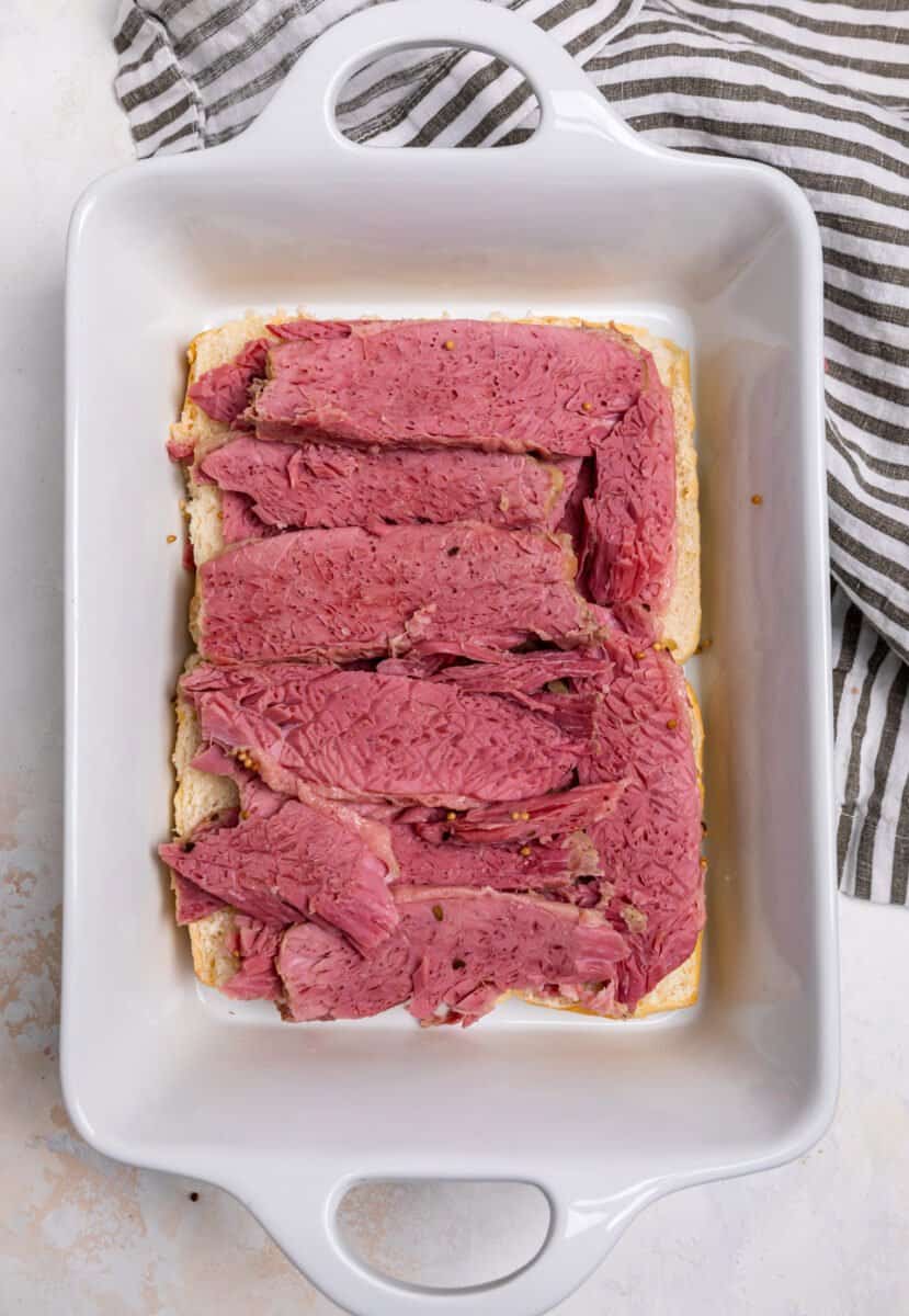 Corned beef sliced and layered on top of rolls.
