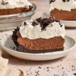 Slice of chocolate pie with chocolate Oreo crust and whipped cream topping.