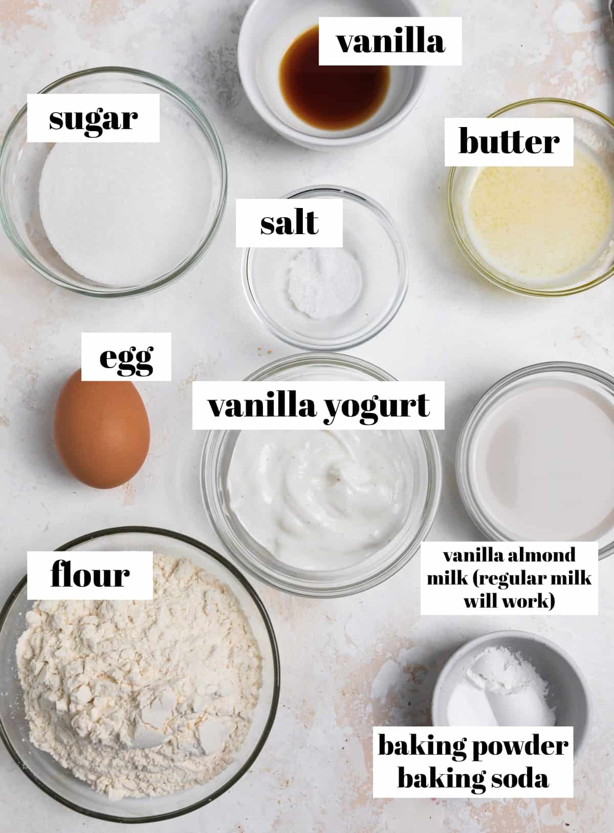 Flour, yogurt, baking powder, butter and other recipe ingredients labeled on a counter.