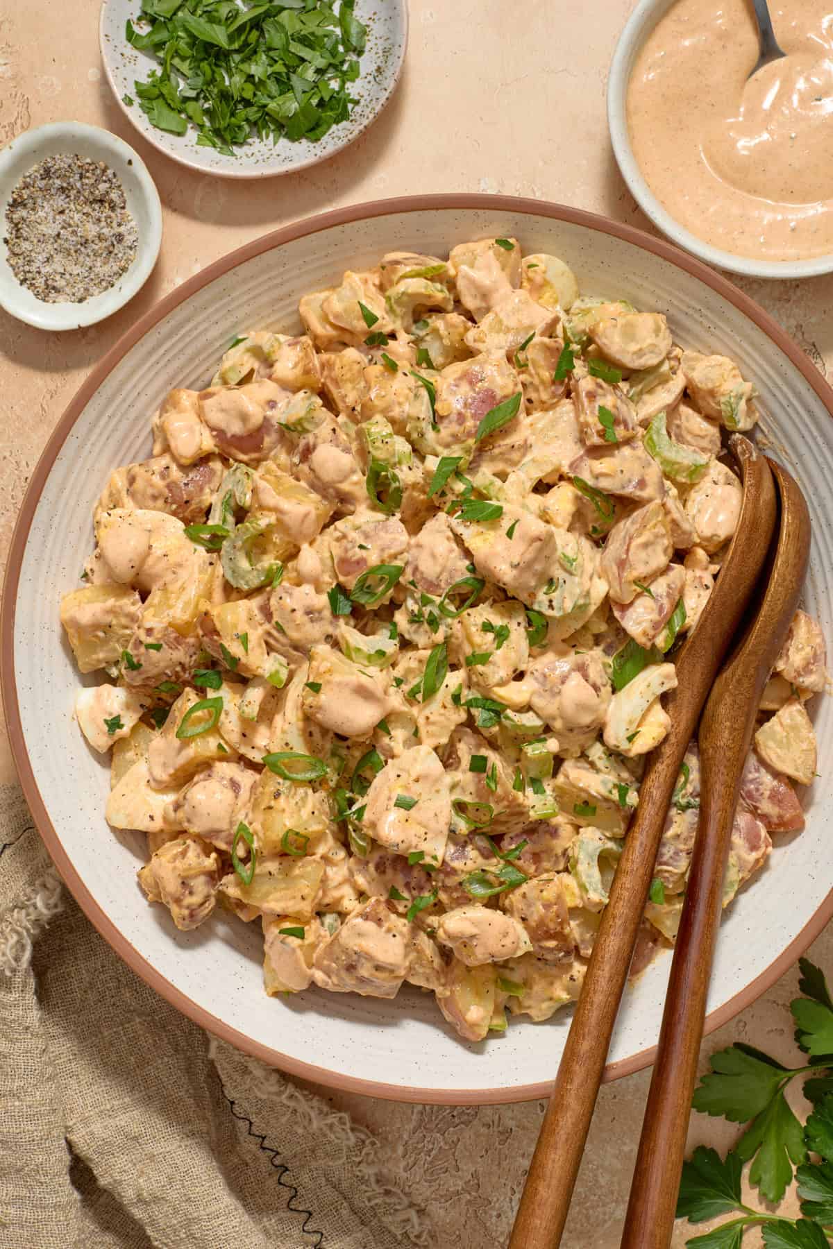 Cajun potato salad in dish with serving utensils propped in bowl.