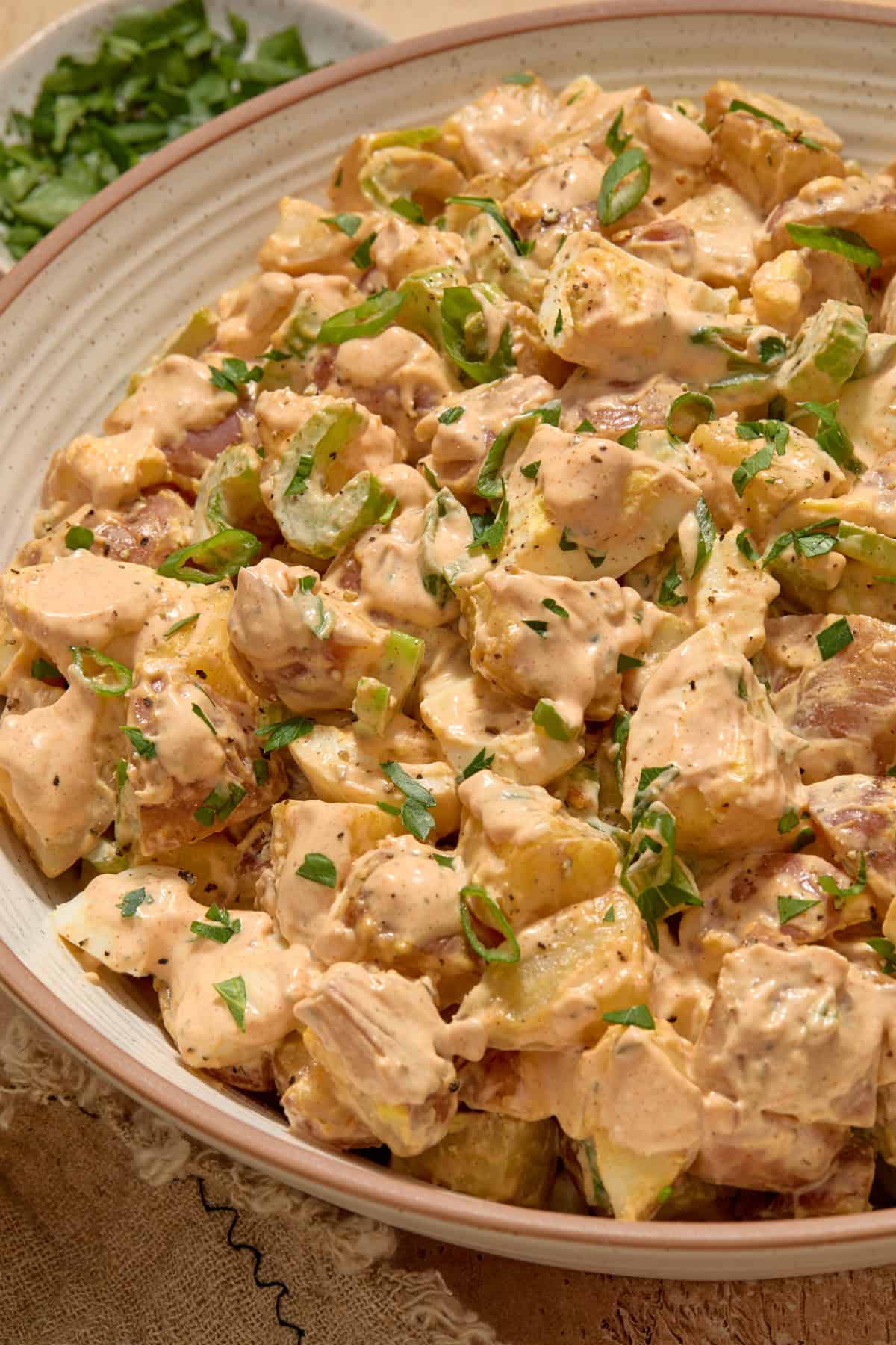 Cajun potato salad in bowl topped with chopped parsley.
