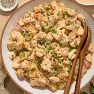 Serving bowl with potato salad and serving utensils.