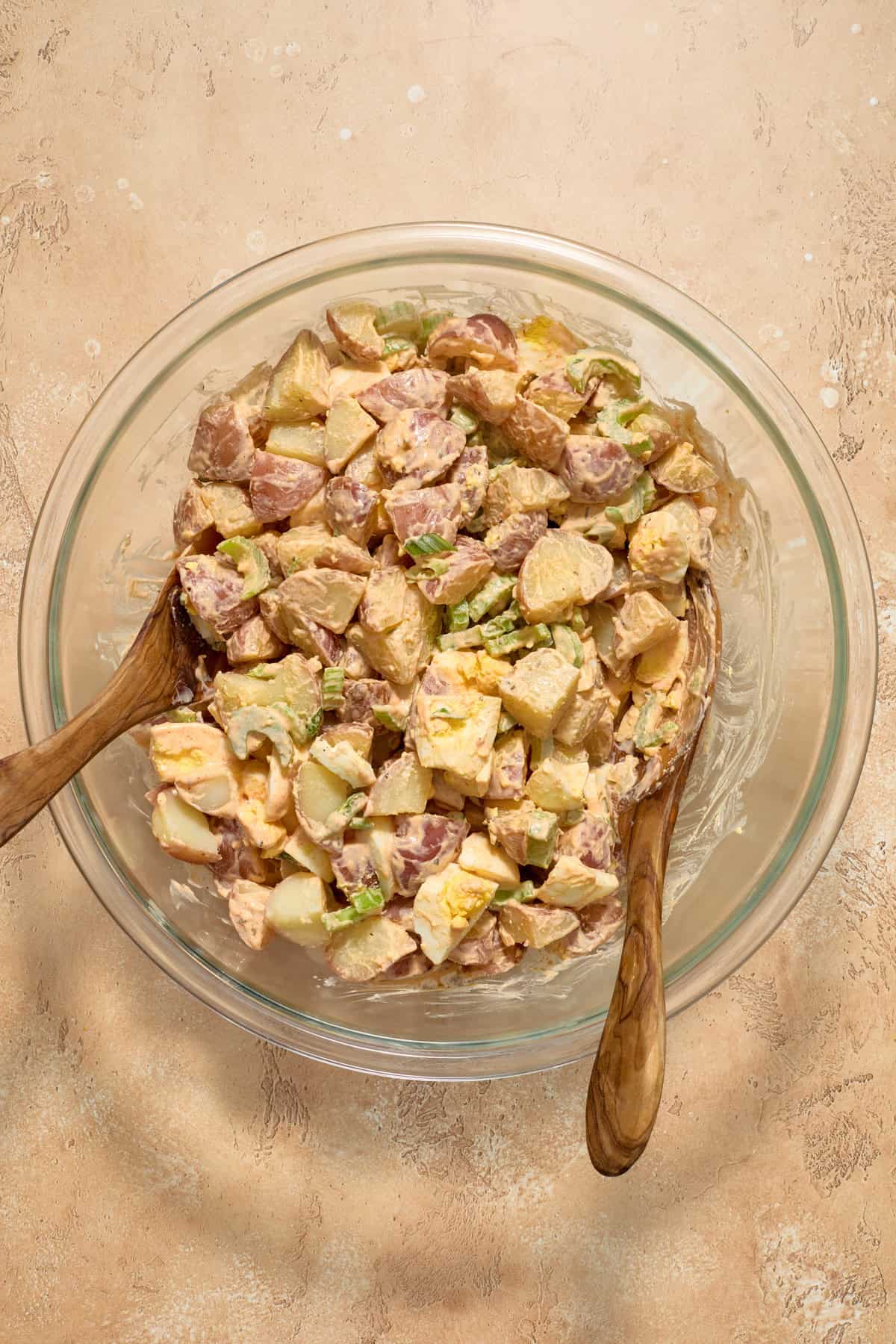 Cajun potato salad in glass bowl after being tossed with dressing.