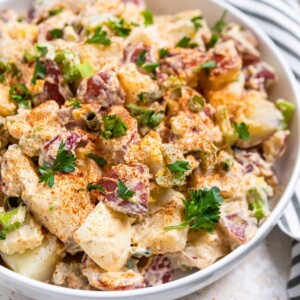 Cajun potato salad in white dish topped with parsley.