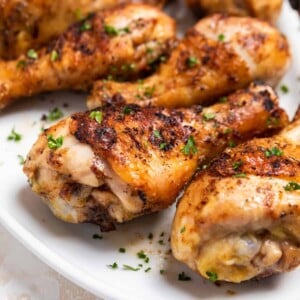 Grilled chicken drumsticks on plate with chopped parsley.