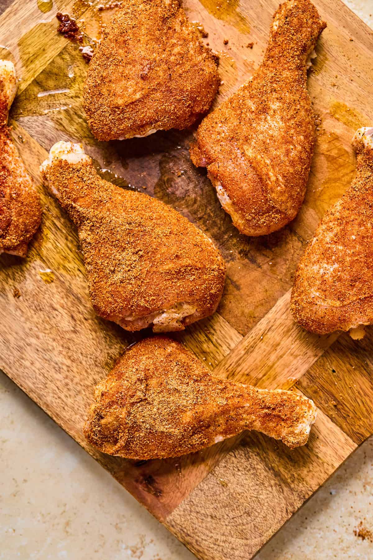 Chicken legs with spice rub covering them before cooking.