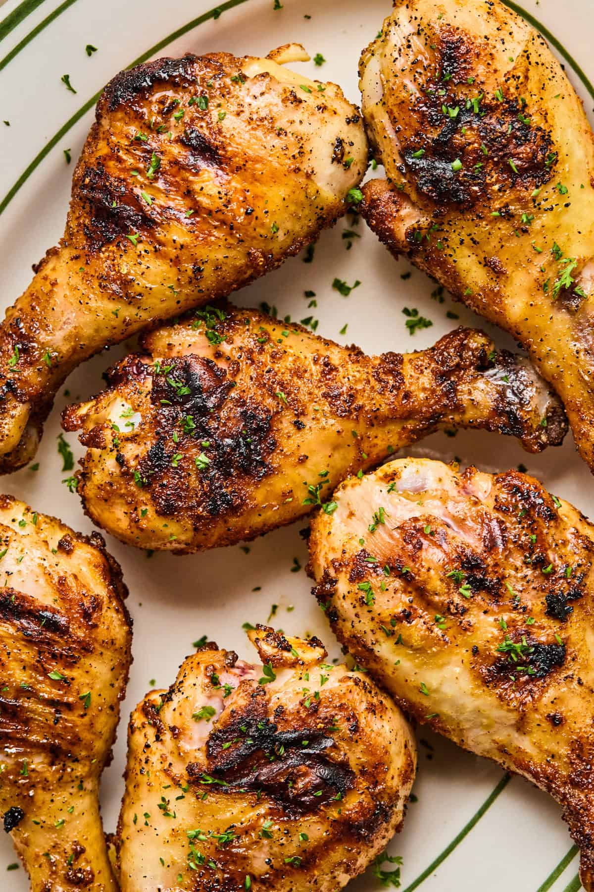 Grilled chicken legs on plate with chopped parsley.