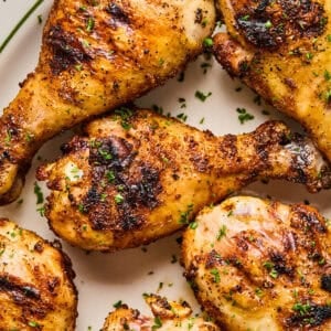 Overhead view of chicken legs grilled on white dish.