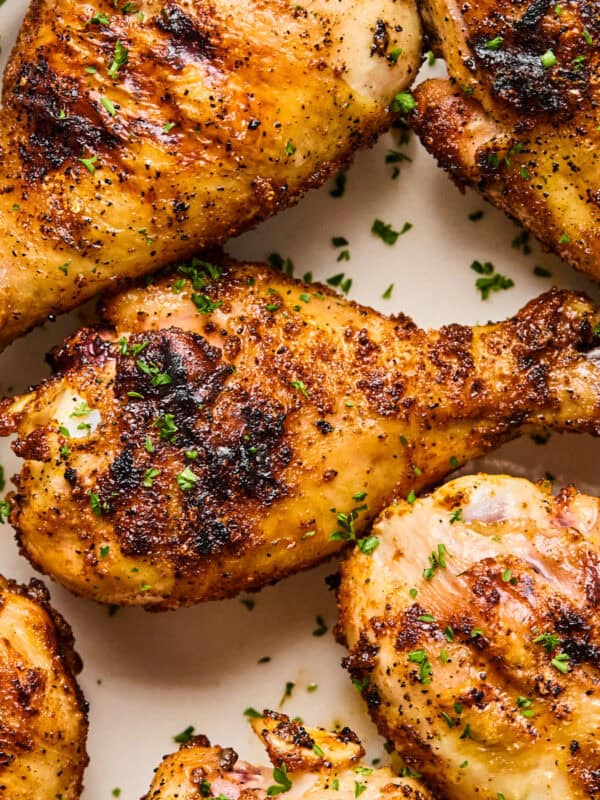 Overhead view of chicken legs grilled on white dish.