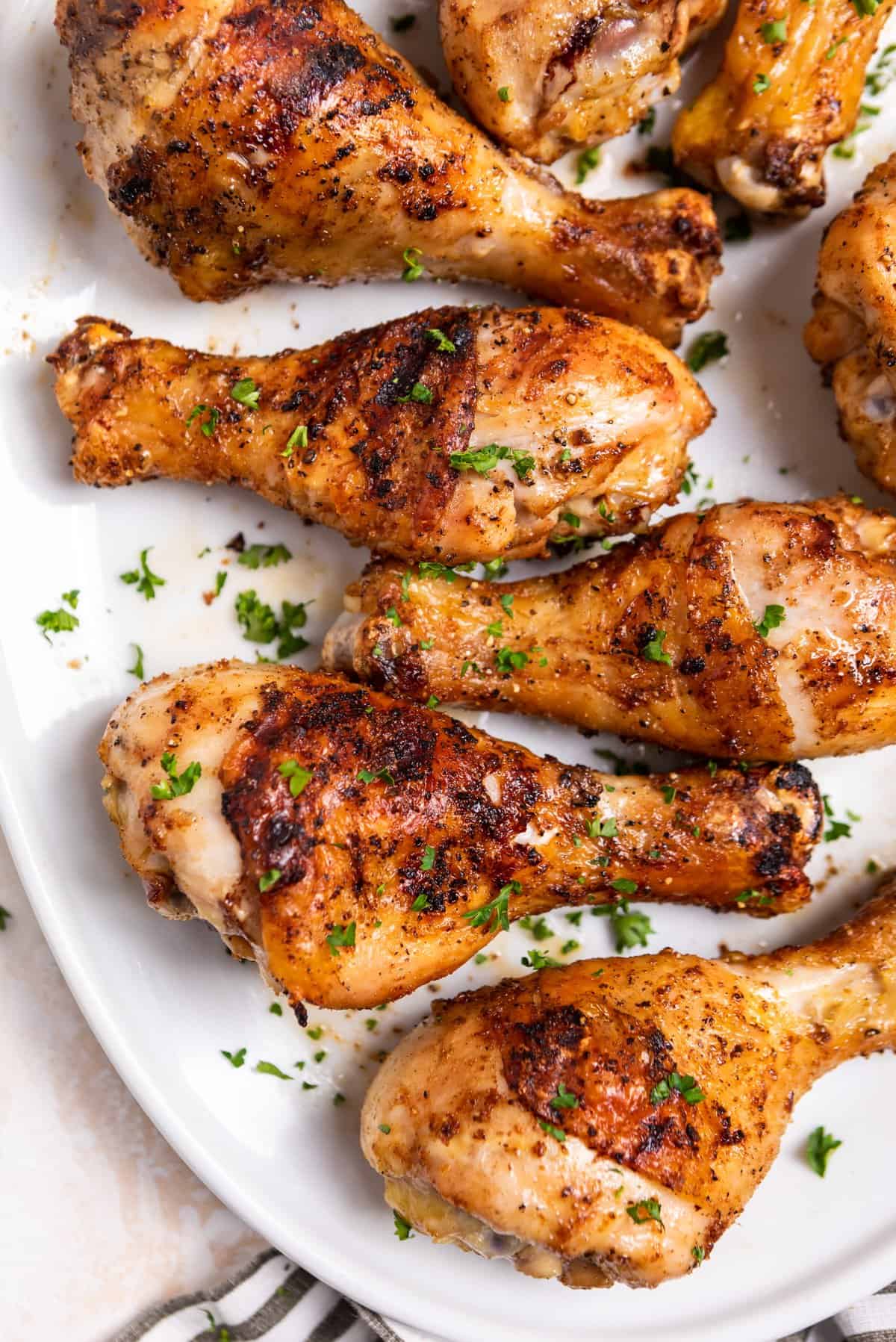 Grilled chicken legs on plate with chopped parsley.