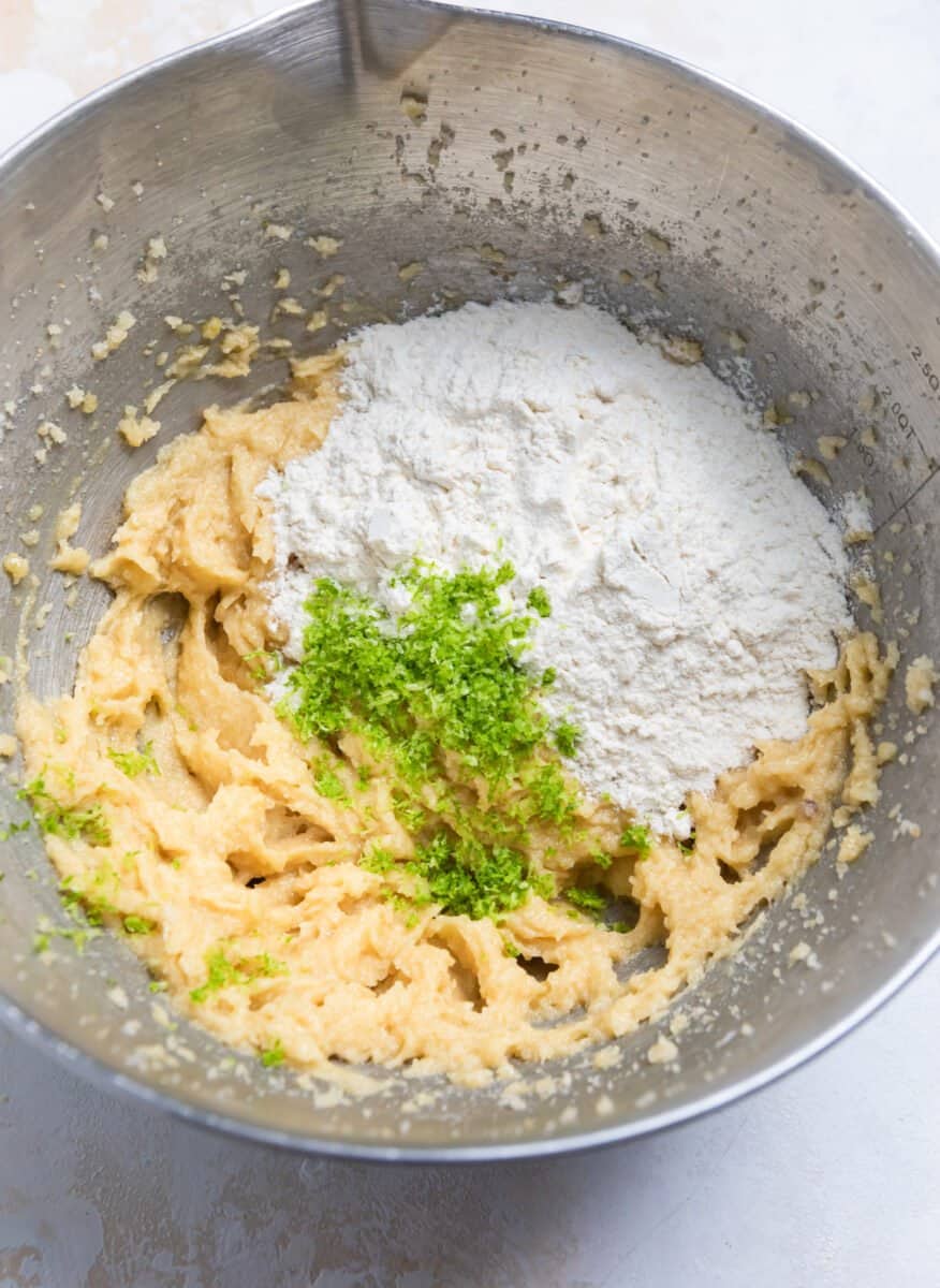 Flour and lime zest added to cookie dough ingredients in mixing bowl.