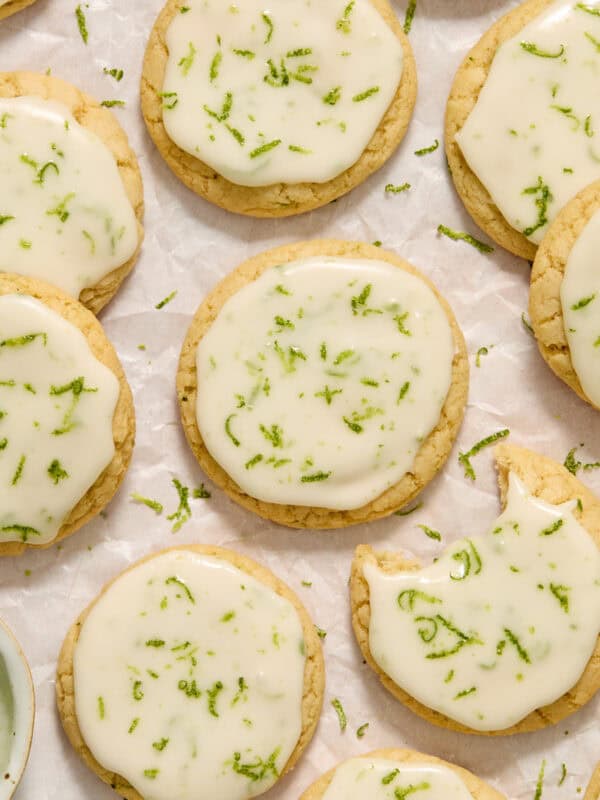 Key lime cookies with lime glaze and zest on surface.