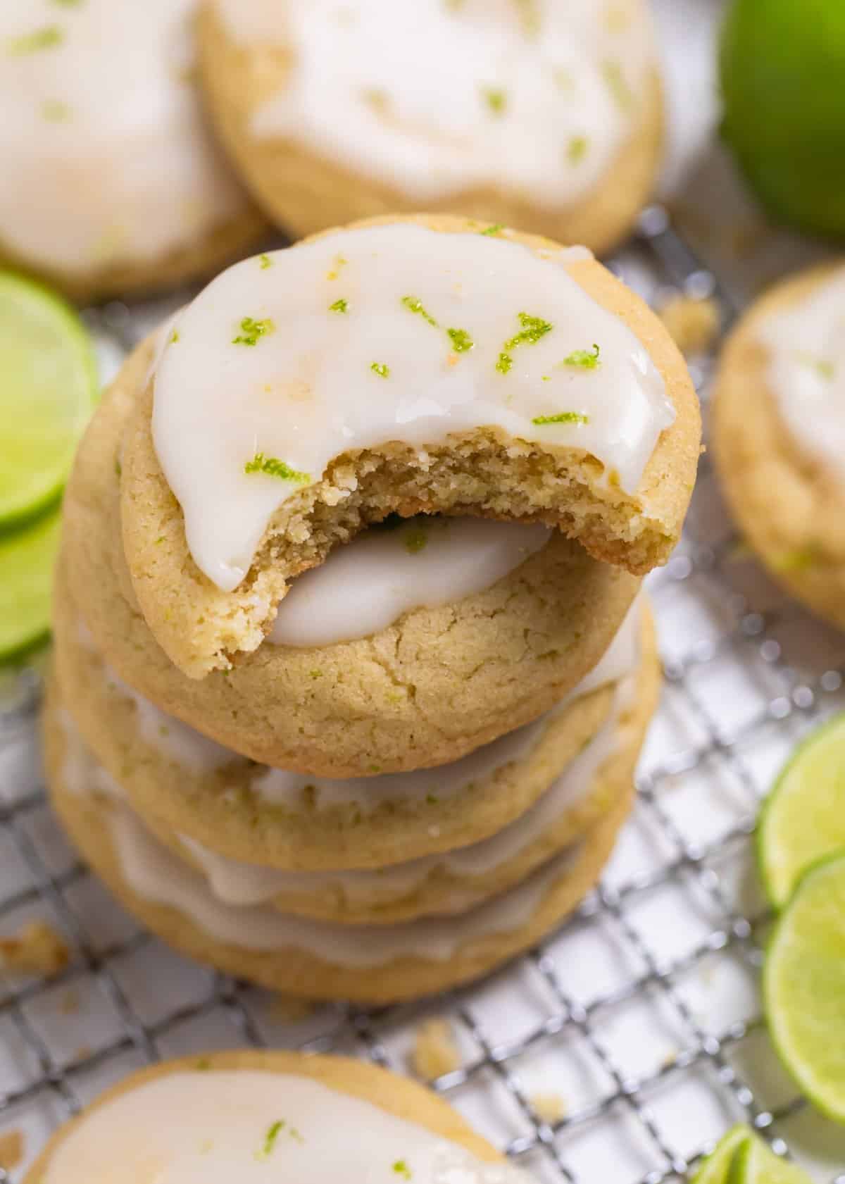 Stack of key lime cookies on cooling rack with bite taken out of top cookie.