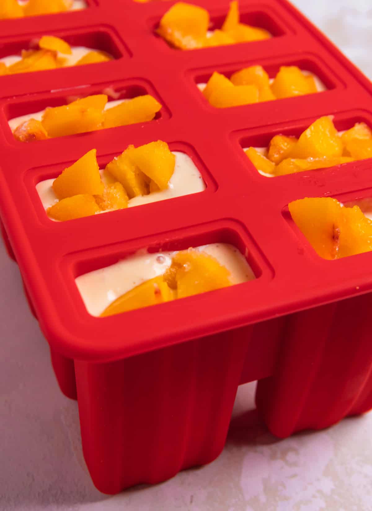 Popsicle molds filled with mixture and topped with peaches.