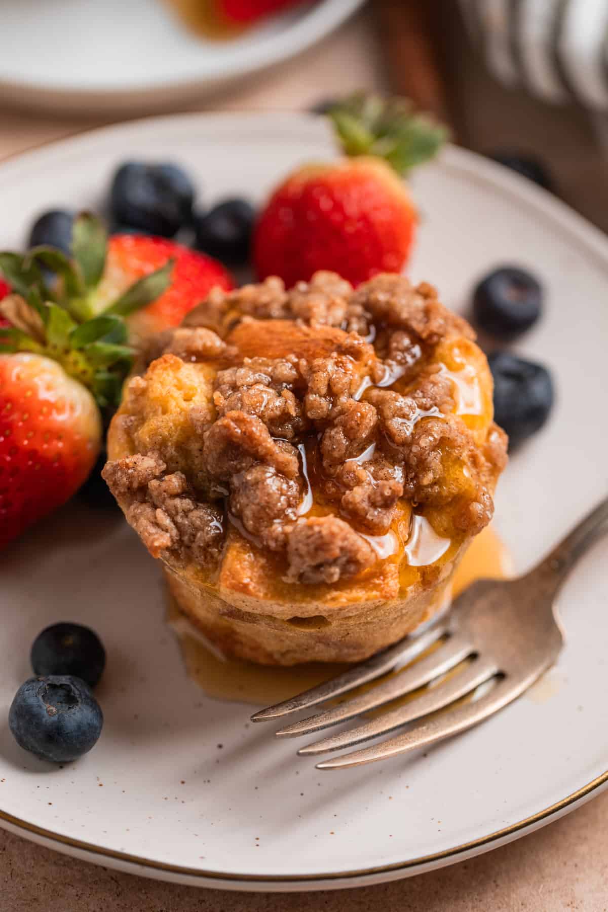 Baked French toast muffin with streusel topping and maple syrup over top.