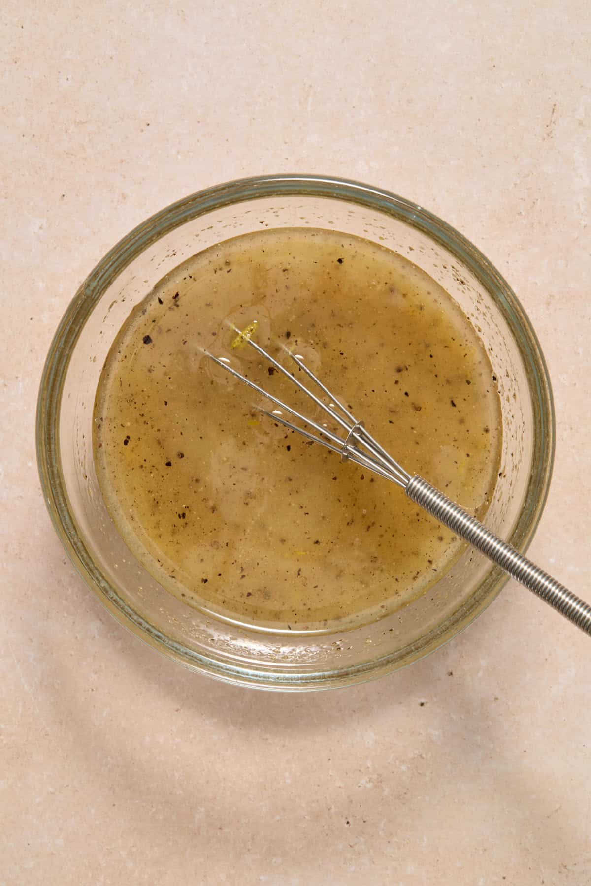 Lemon marinade in glass bowl with whisk.
