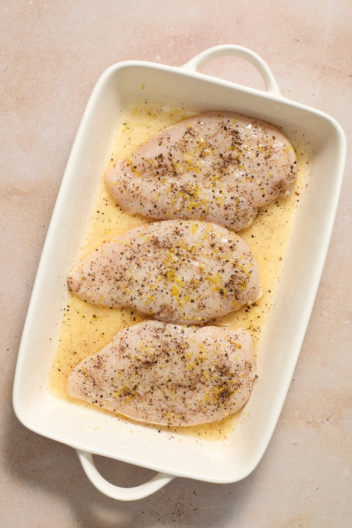Marinated chicken in dish with lemon and pepper.