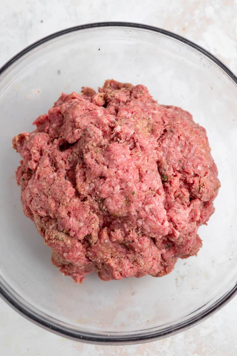 Ground beef mixture in glass mixing bowl.