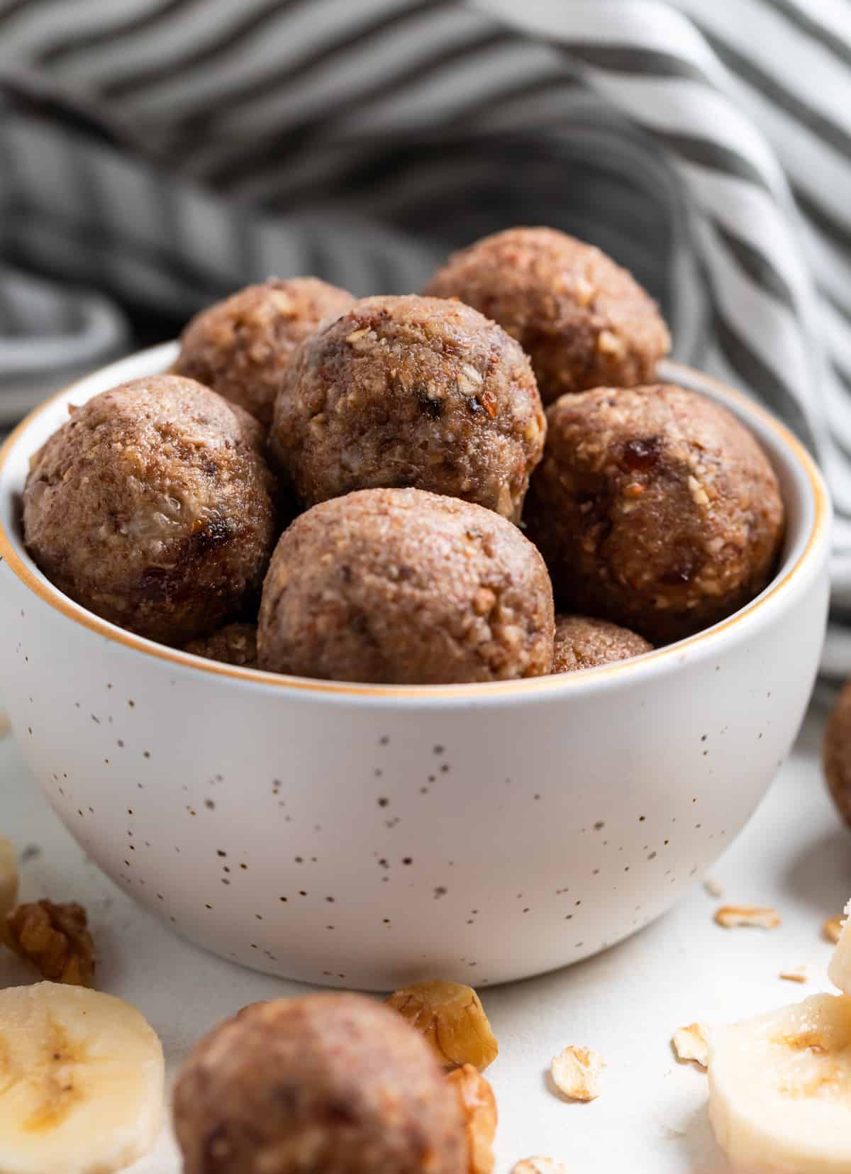 Banana oat balls in bowl with linen behind.