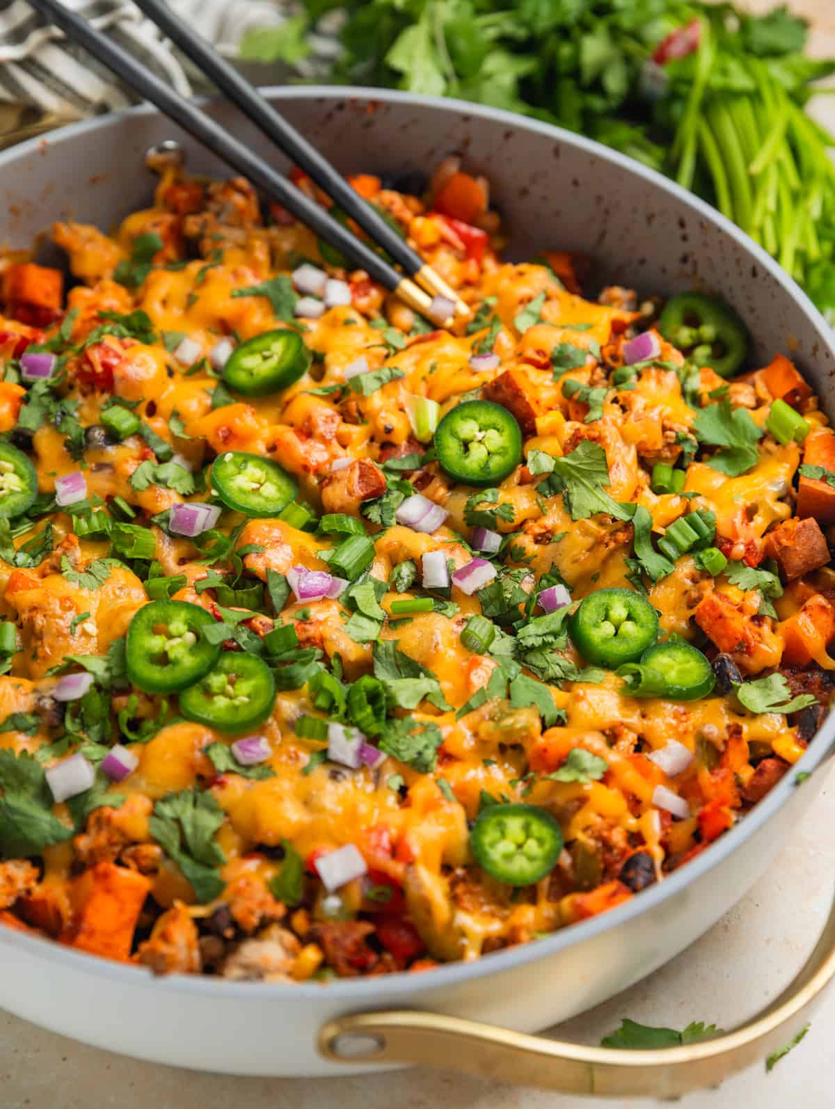 Ground turkey and sweet potato skillet dinner in skillet topped with jalapeños, cilantro, onion and more.