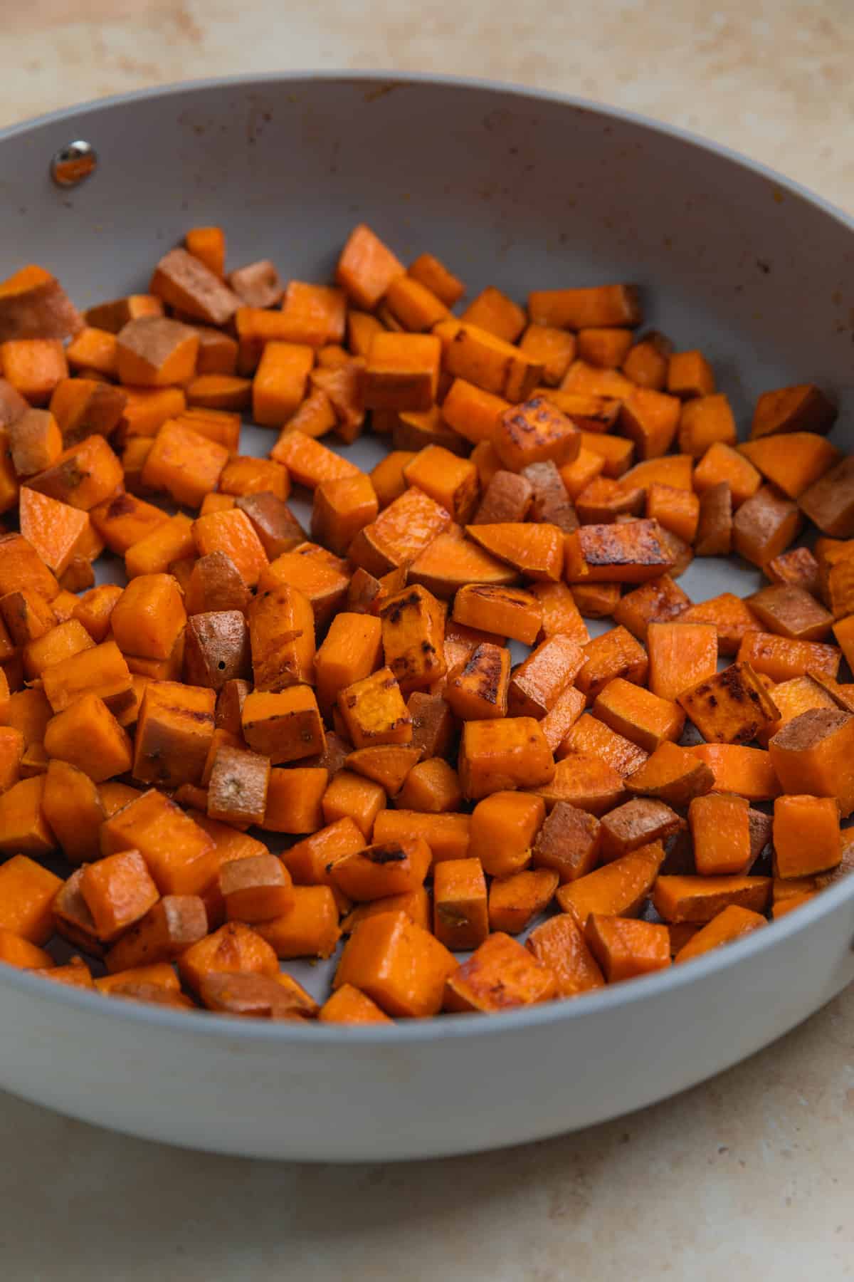 Sweet potatoes cooked in an even layer in skillet.