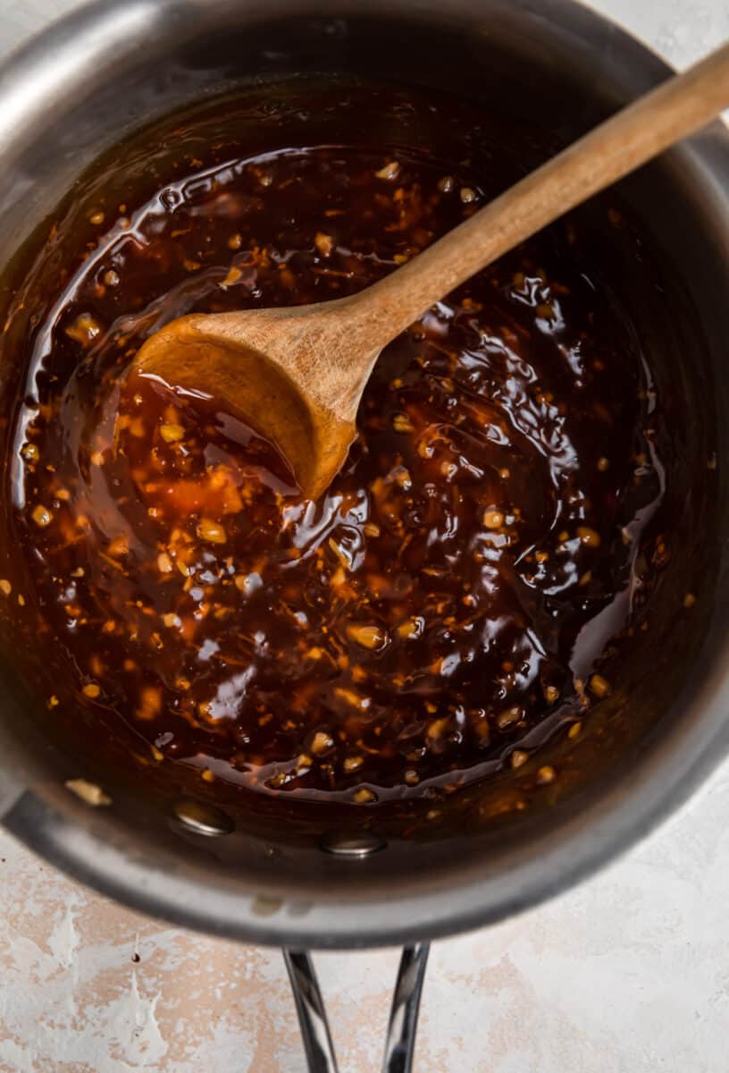 Teriyaki sauce prepared in sauce pan with wooden spoon placed inside.