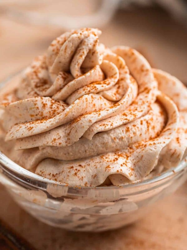 Pumpkin spice whipped cream piped in glass bowl with cinnamon dusted over top.