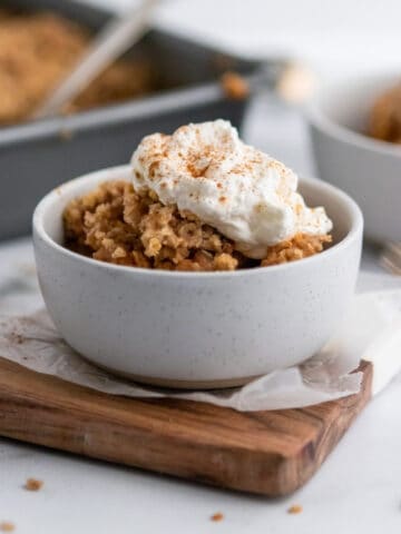 Pumpkin crumble dessert in bowl with whipped topping.