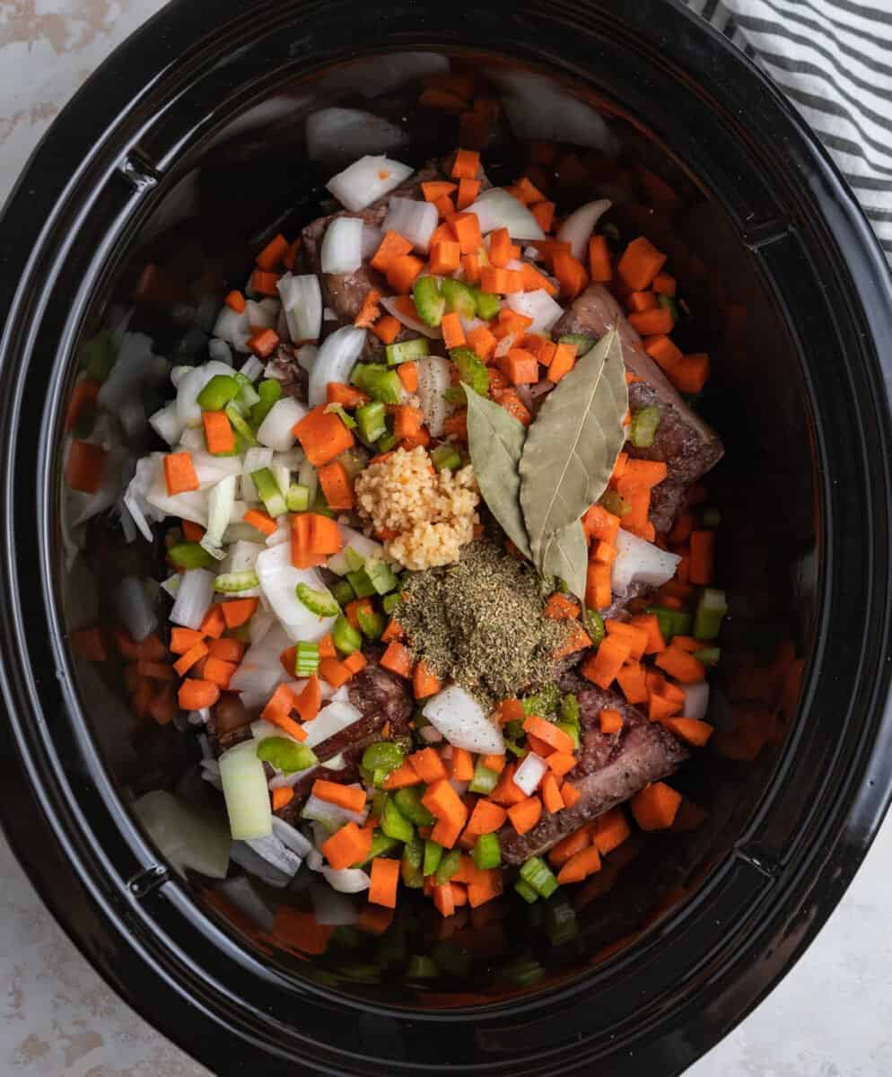 Carrots, onion, celery and ingredients over short ribs in crock pot.
